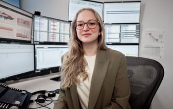 Kvinna sitter vid skrivbord och tittar in i kameran Kvinna sitter vid skrivbord och tittar in i kameran