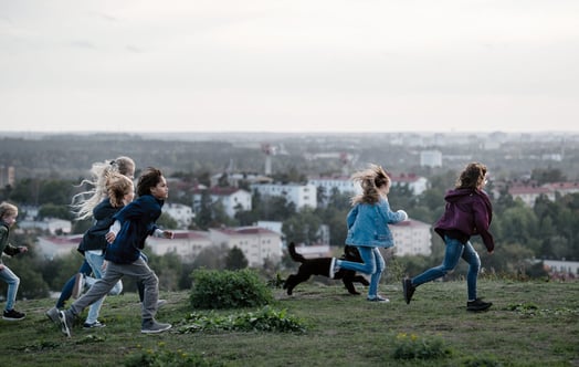 En grupp barn som springer på en kulle